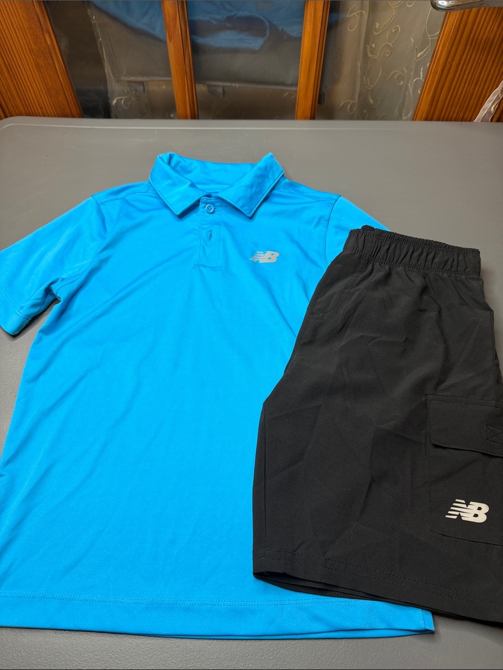 Kid’s New Balance Bright Blue Polo and Black Athletic Shorts Set. Size: 8